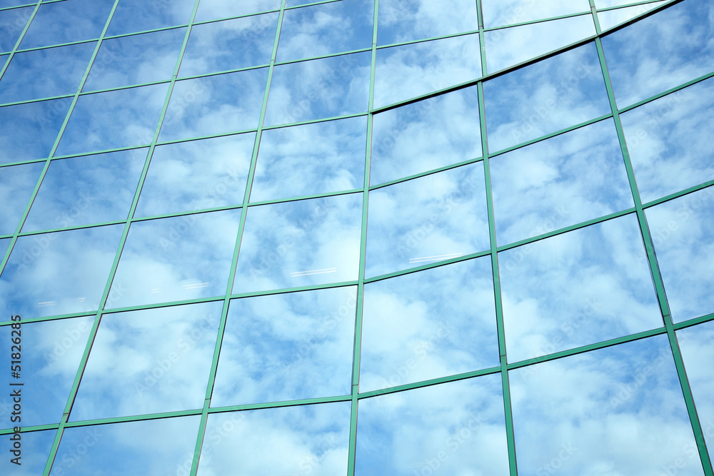reflections of blue sky and clouds in curved facade