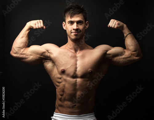 Waist-up portrait of muscular man flexing his biceps