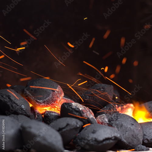 Charcoal briquettes with fire sparks.