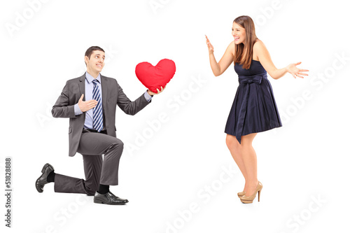 Romantic man giving a red heart to a young woman