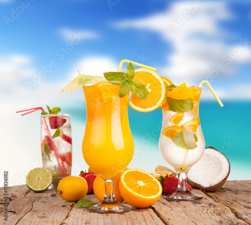 Fresh summer drinks on wooden table with blur sea background
