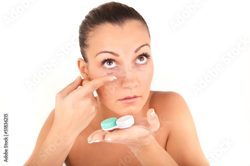 woman inserting a contact lens in her eye
