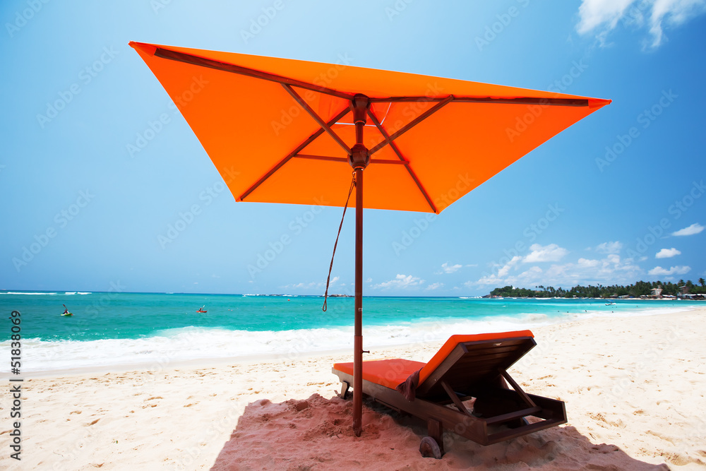Tropical beach at Indian Ocean. Red umbrella and lounge at the s Tropical beach at Indian Ocean. Red umbrella and lounge at the s