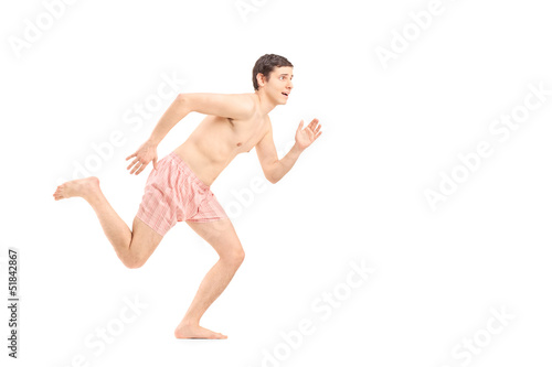 An embarrassed naked man in underwear running away