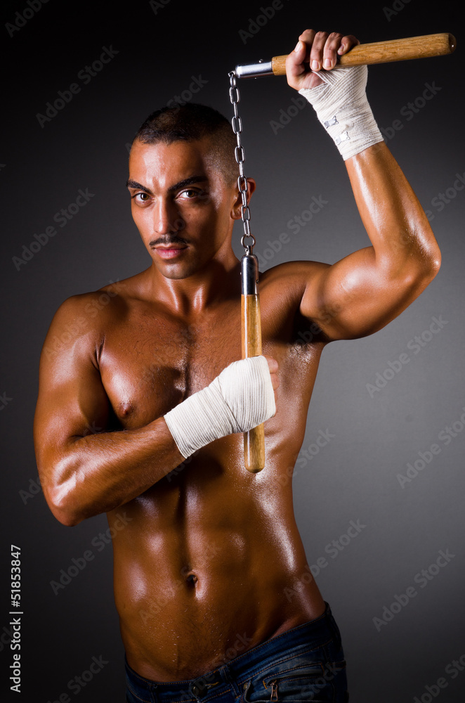 Muscular man with nunchucks on white Muscular man with nunchucks on white