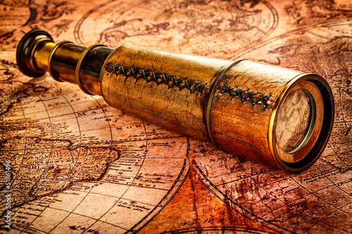 Vintage spyglass lies on an ancient world map photo