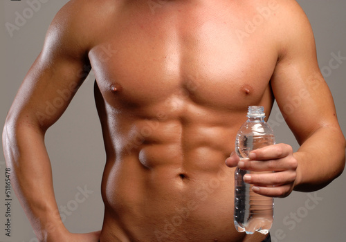 Hombre musculoso sujetando una botella de agua potable.