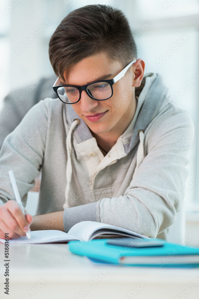 High School students. Handsome male student making notes in clas High School students. Handsome male student making notes in clas