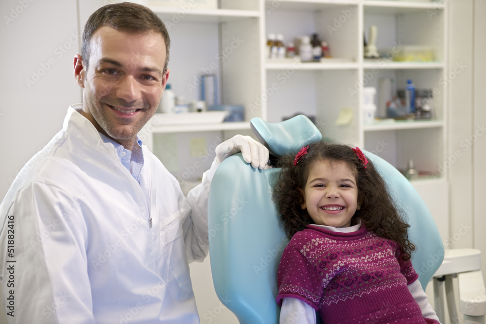Fototapeta premium Portrait of child and dentist in dental studio, looking at camer
