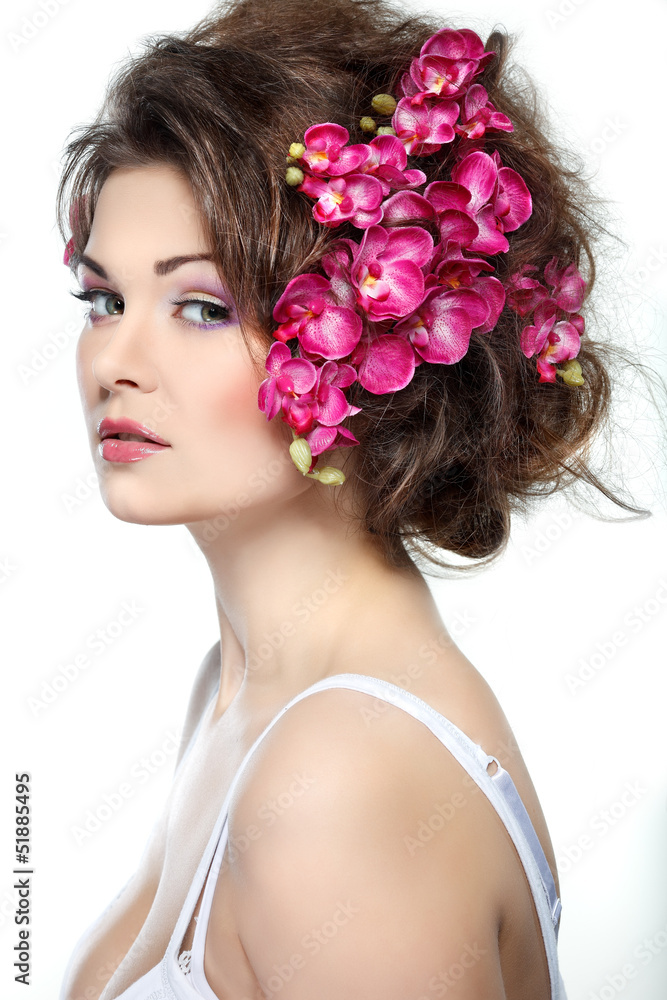 Portrait of beautiful sexual brunette with pink orchids in hairs