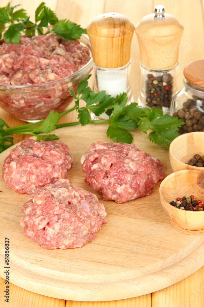 Raw meatballs with spices on wooden table