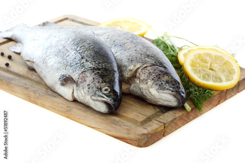 Fresh fish and lemon on wooden board.