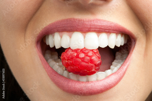 Perfect teeth biting raspberry. photo