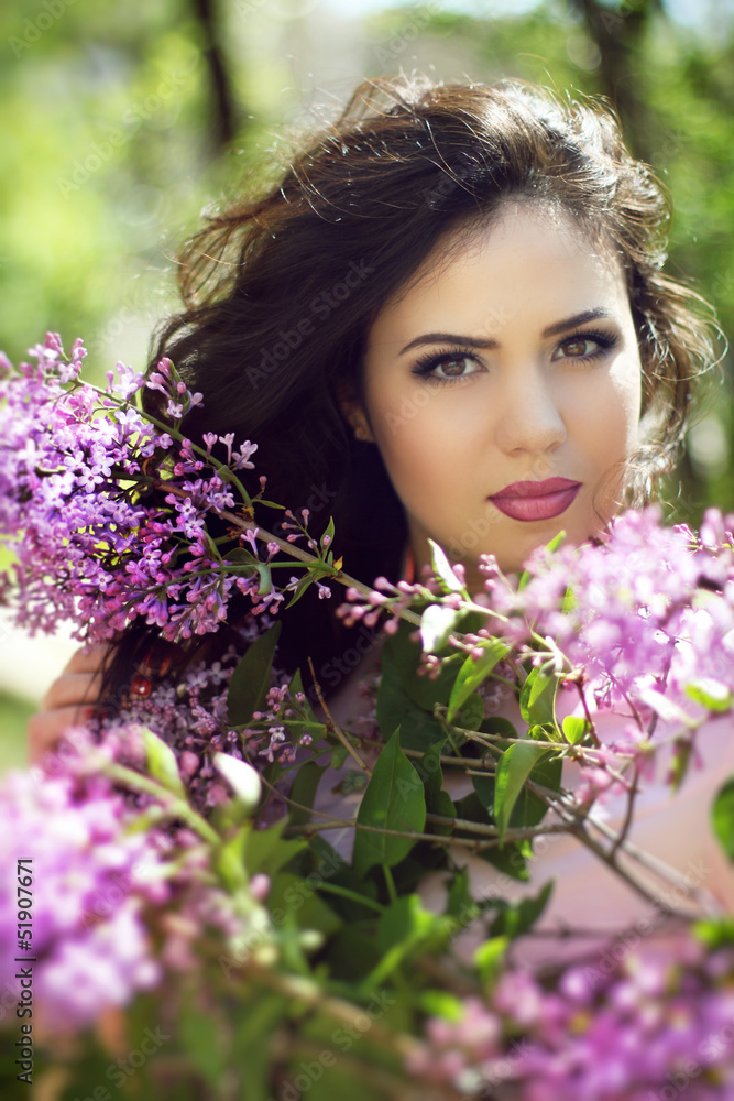 Fototapeta premium Young brunette woman with lilac flowers, Outdoors portrait