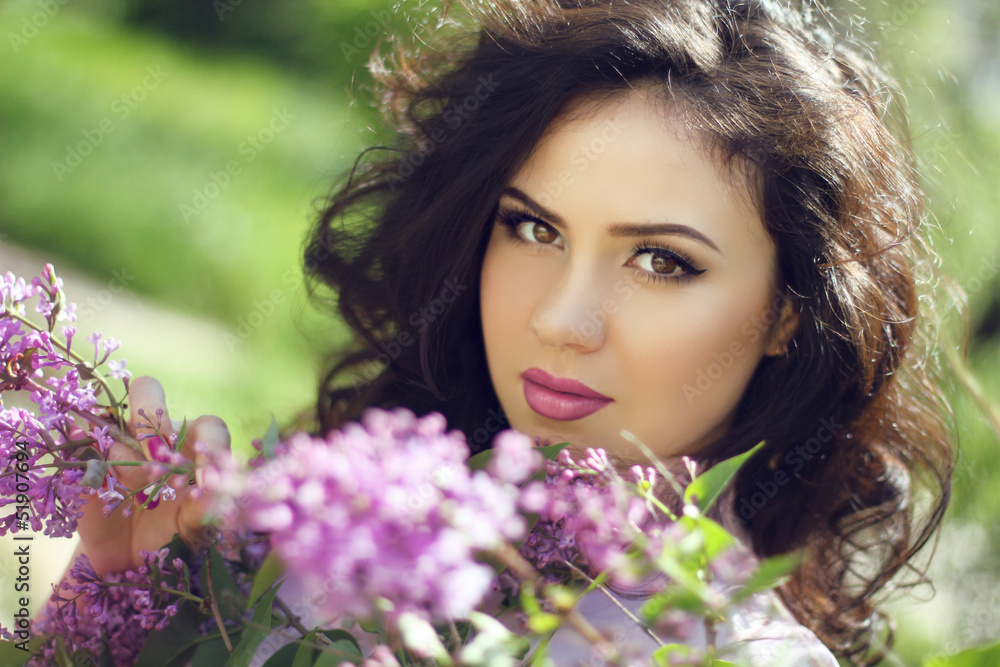 Young brunette woman with lilac flowers, Outdoors portrait
