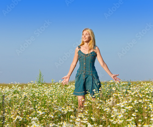 The beautiful happy young woman in the field of chamomiles...