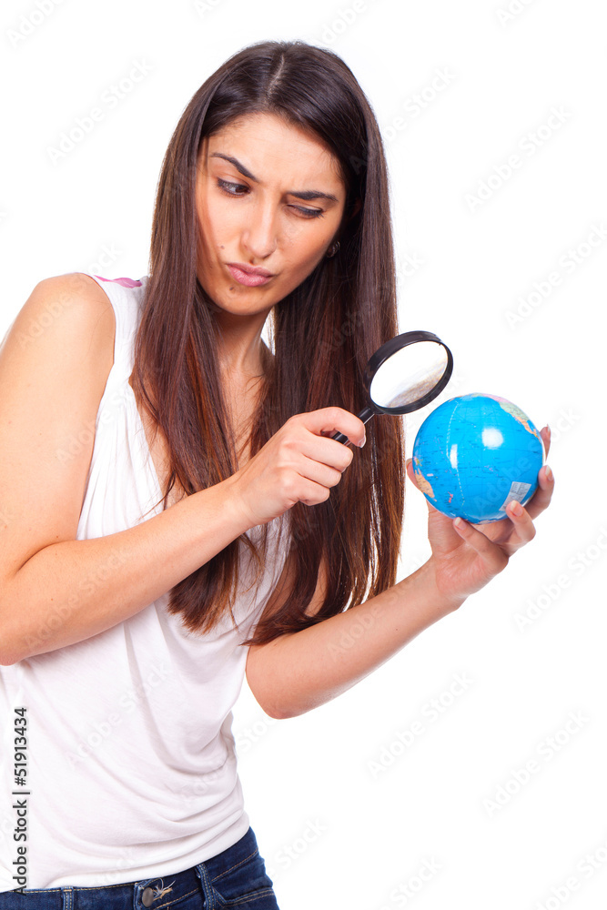 Pretty female holding a globe and using a magnifying glass while Pretty female holding a globe and using a magnifying glass while