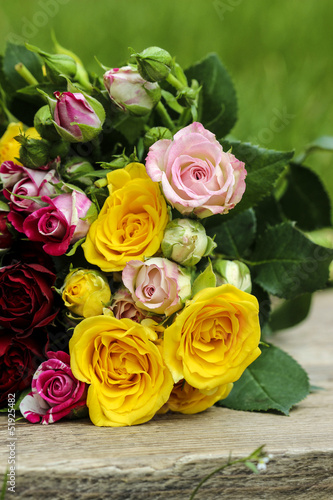 Fabulous bouquet of colorful roses on wooden tray in fresh sprin