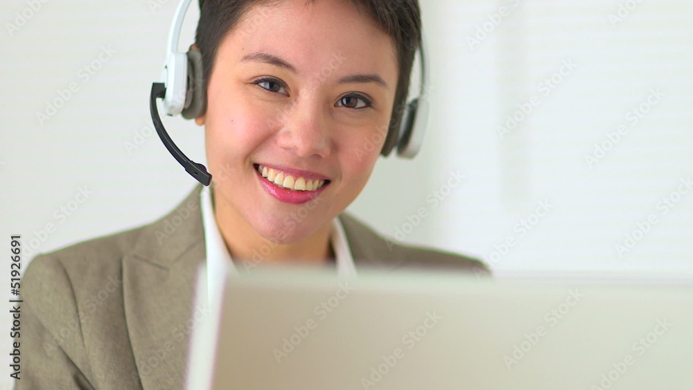 Asian customer service representative with headset in call cente Asian customer service representative with headset in call cente