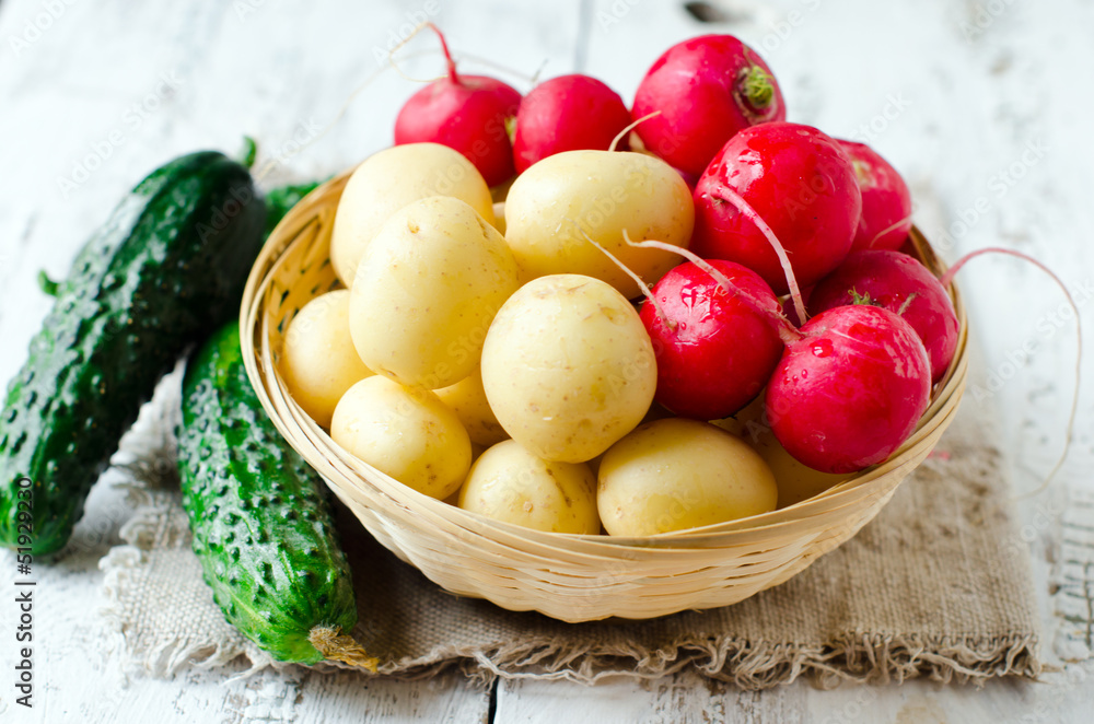 .Fresh young potatoes , cucumbers and radishes in a basket .Fresh young potatoes , cucumbers and radishes in a basket