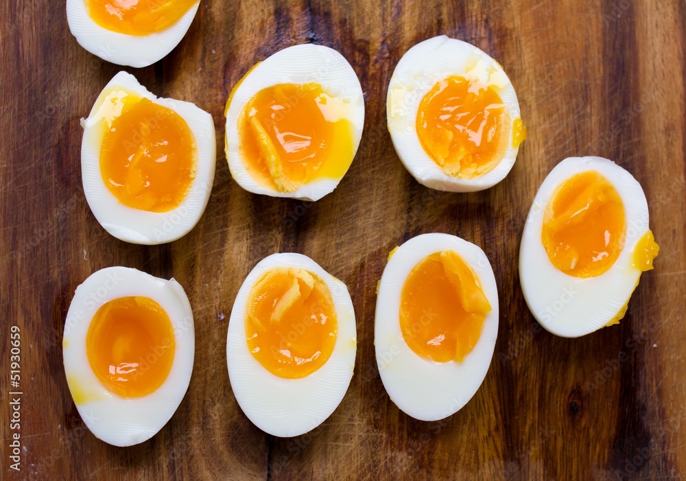 Hard boiled eggs, sliced in halves on wooden background Hard boiled eggs, sliced in halves on wooden background