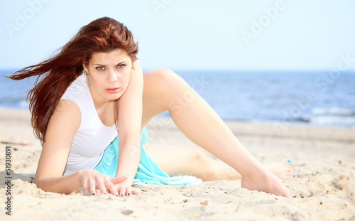 young woman on seacoast with shell on sand
