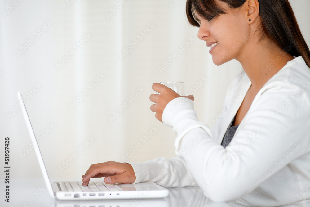 Young woman drinking and working on laptop Young woman drinking and working on laptop