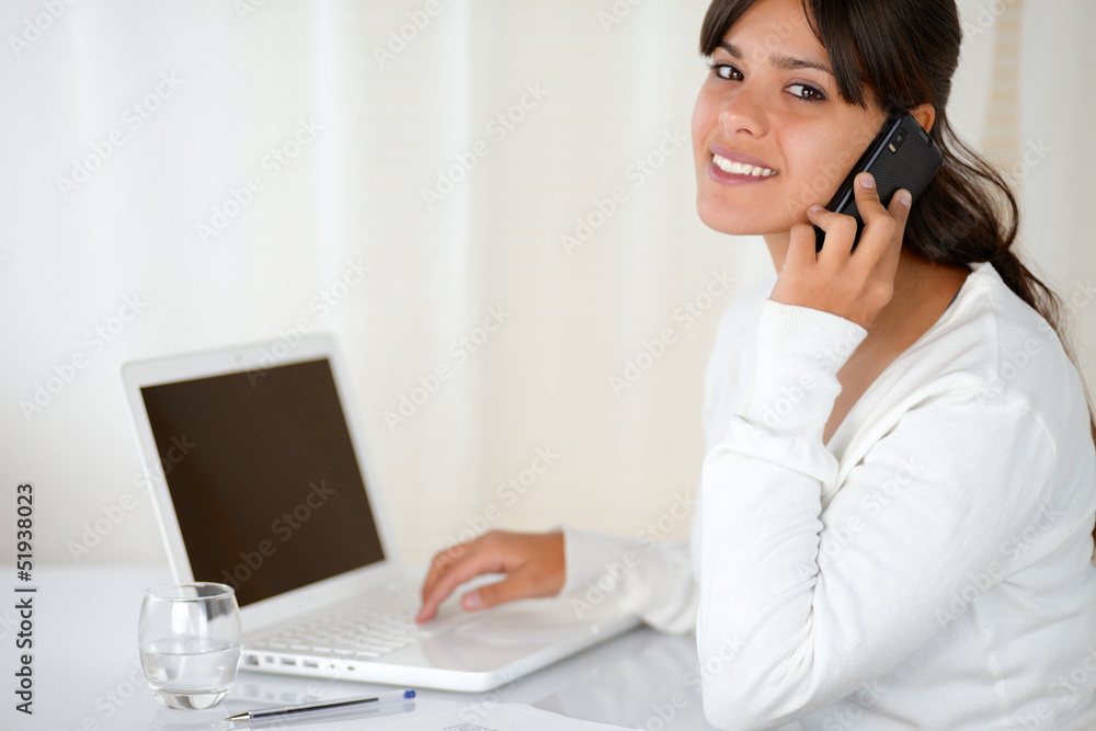 Young woman speaking on cellphone looking at you Young woman speaking on cellphone looking at you