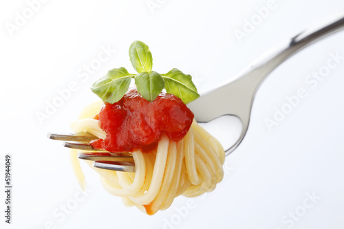 Spaghetti pasta with tomato sauce and basil on fork