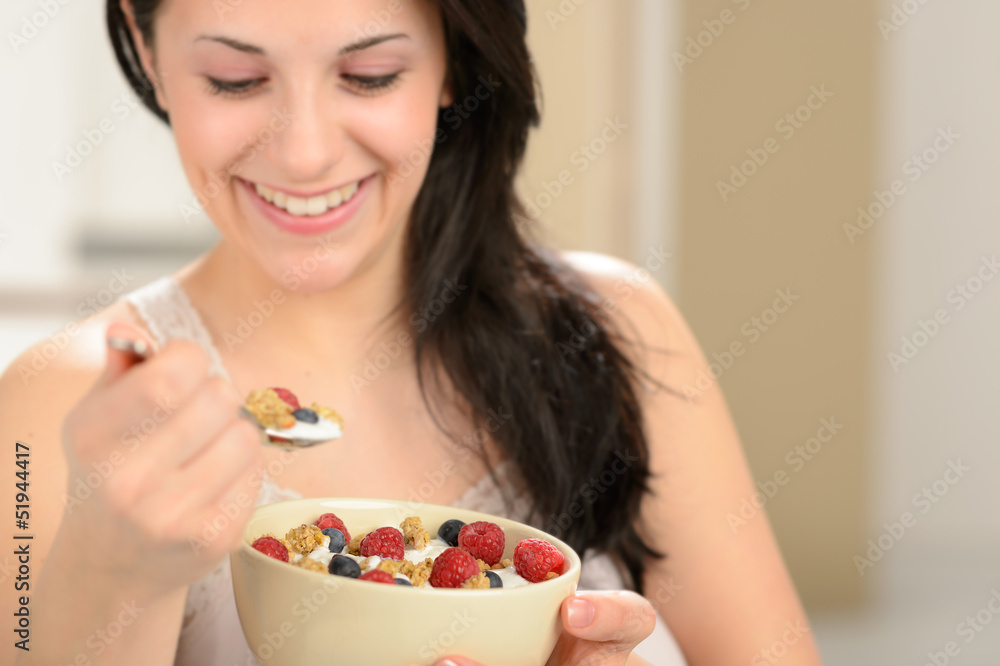 Joyful woman eating healthy cereal for breakfast