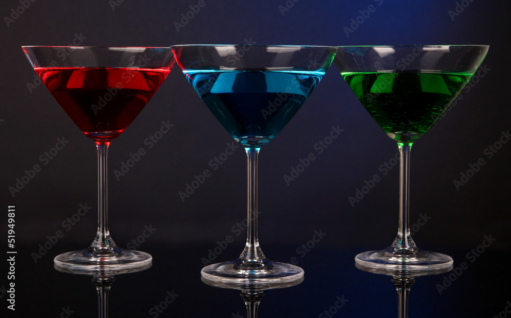 Alcoholic cocktails in martini glasses on dark blue background Alcoholic cocktails in martini glasses on dark blue background