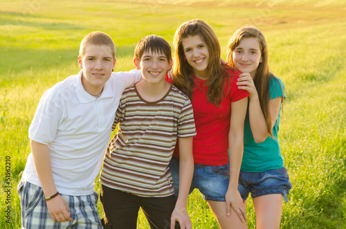 Four teenage boys and girls having fun on the meadow