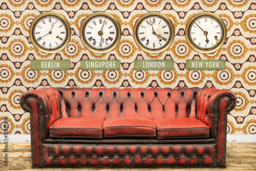 Retro chesterfield sofa with world time clocks on a wall photo