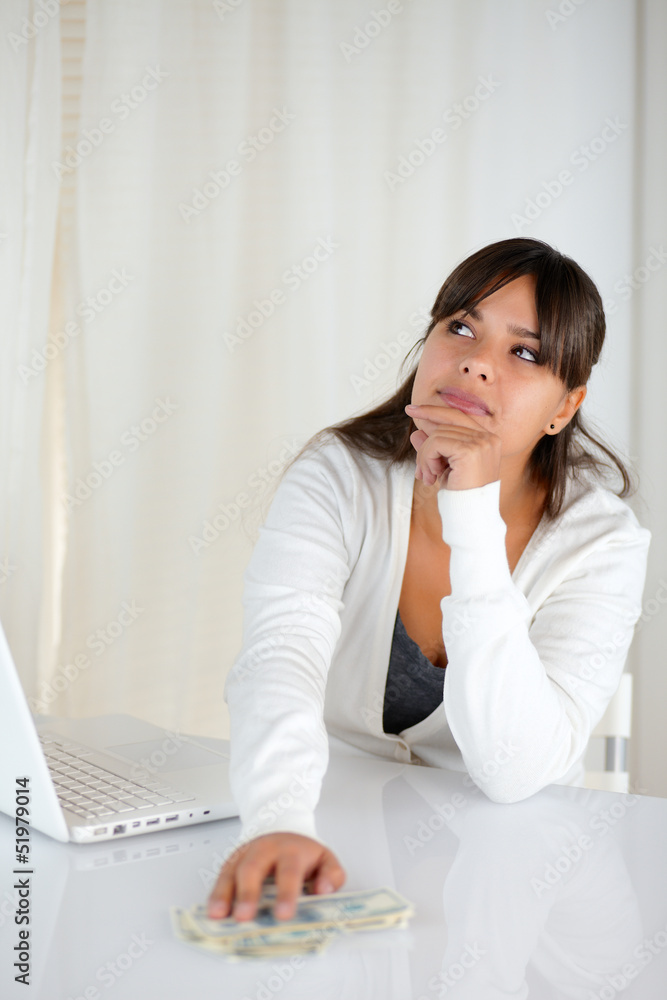Young woman thinking with cash money Young woman thinking with cash money