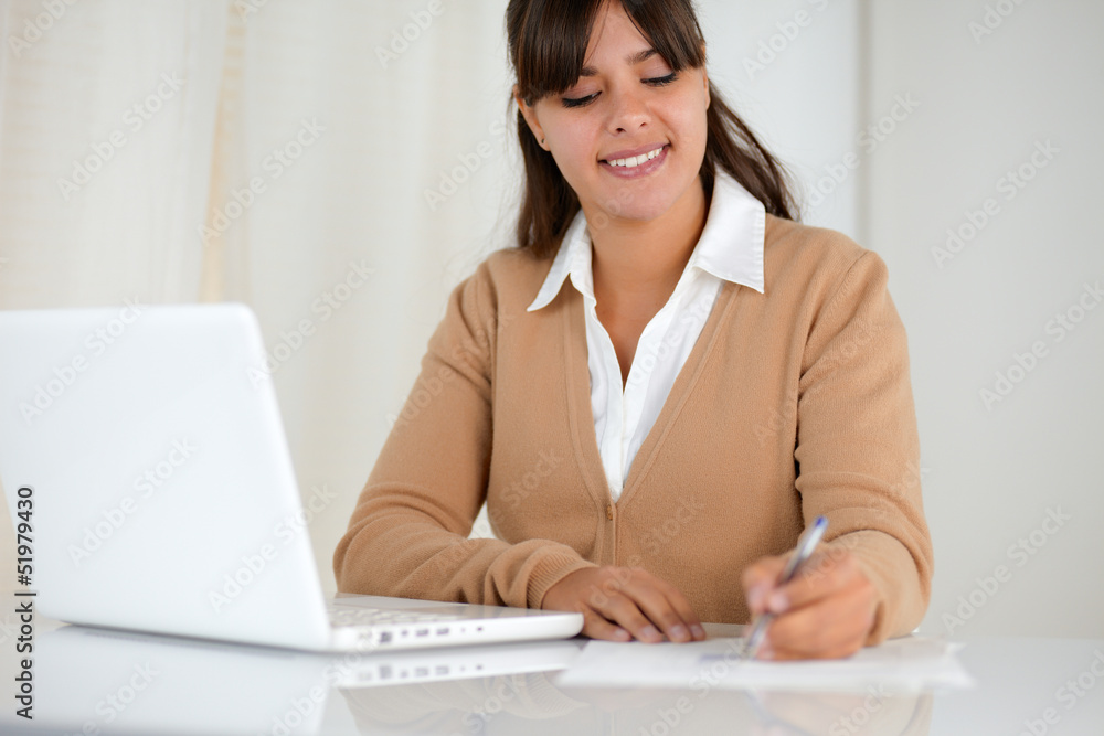 Young woman reading documents and using laptop Young woman reading documents and using laptop