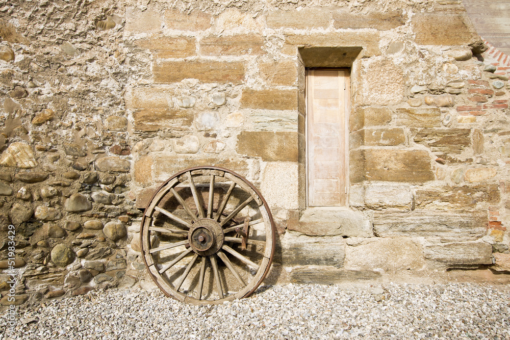 Ancient rural facade detail.Old wooden wagon wheel