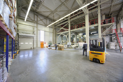 Men in gray uniform work in large warehouse
