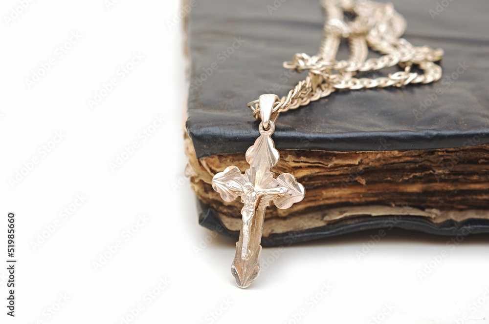 Fototapeta premium Religion. A cross with a chain against a old book