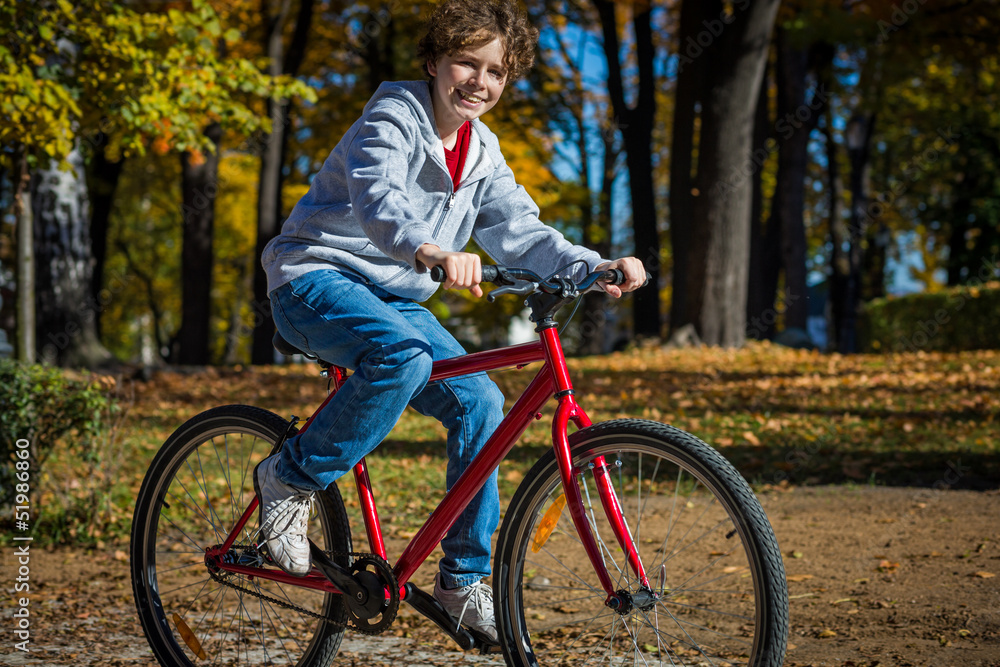 Urban biking - teenage boy riding bike in city park