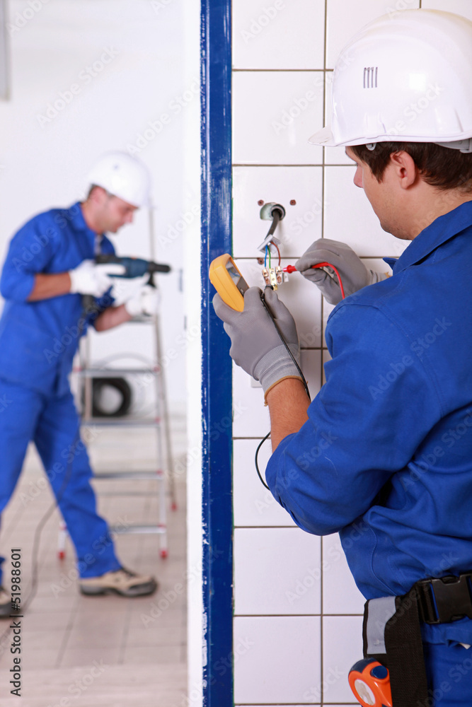Electrician testing a light switch with a multimeter Electrician testing a light switch with a multimeter