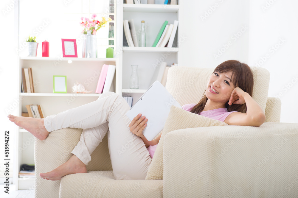 Beautiful smiling Asian woman with tablet computer. Lying on sof Beautiful smiling Asian woman with tablet computer. Lying on sof
