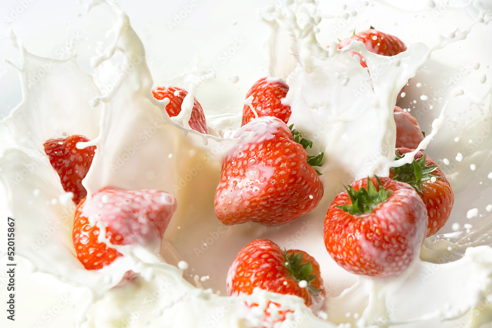 Fototapeta premium Red strawberry fruits falling into the milk