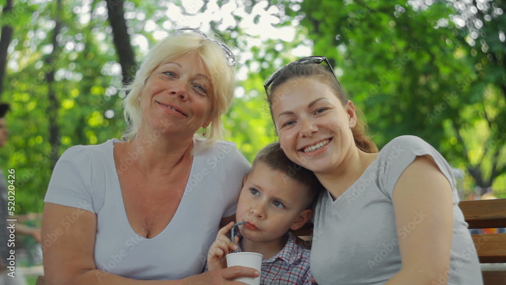 child drinks juice, mother and grandmother smiling child drinks juice, mother and grandmother smiling