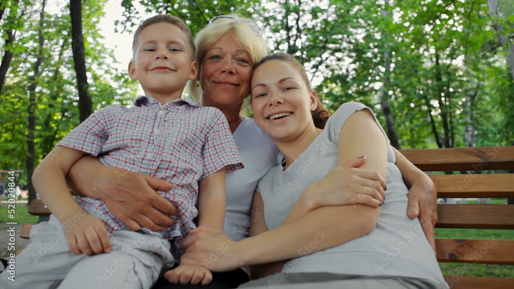 happy grandmother hugs her daughter and grandson on a bench happy grandmother hugs her daughter and grandson on a bench