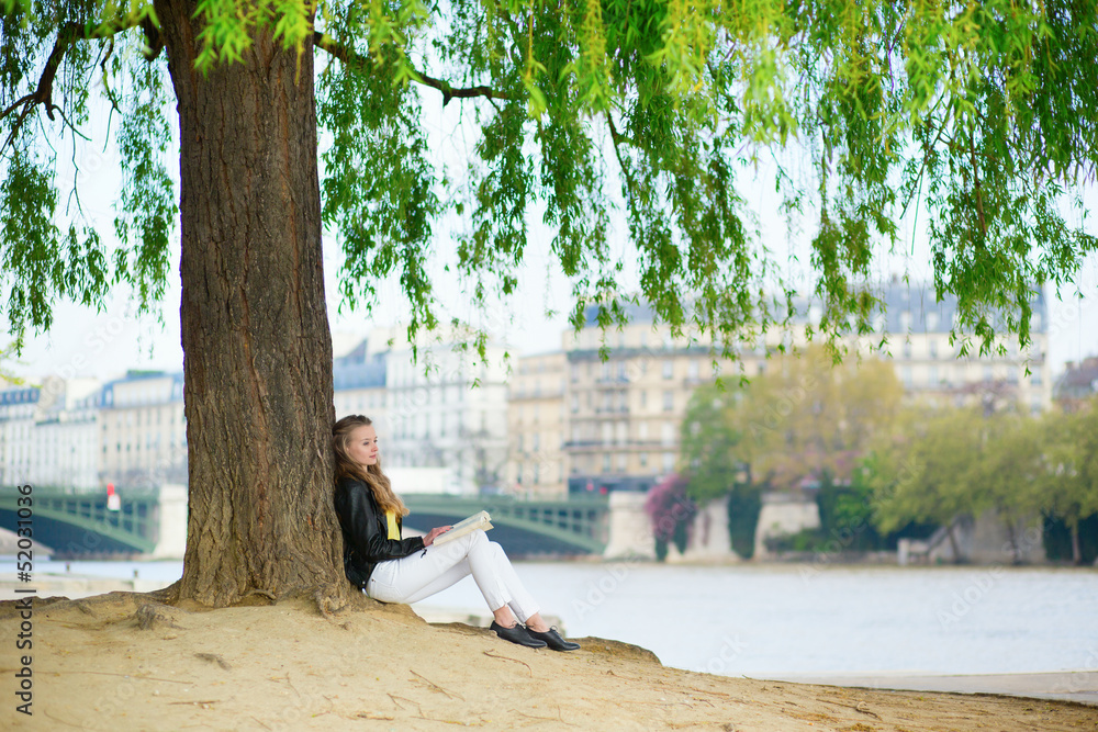 Girl reading a book under the tree