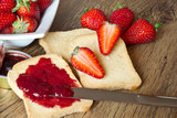 strawberries jam with rusk on wooden table