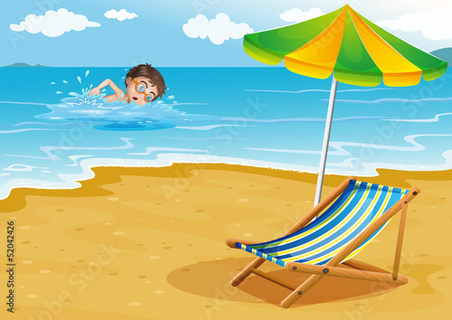 A boy swimming at the beach with an umbrella and a bed