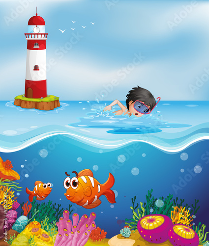 A boy swimming at the beach near the lighthouse