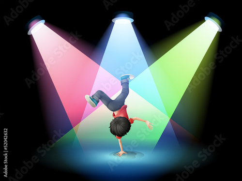 A boy breakdancing at the stage with spotlights