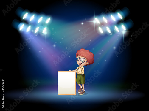 A boy holding an empty frame on the stage with spotlights